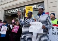 Os ativistas John Bosco (algemado) e Bisi Alimi (segurando o cartaz) protestam usando niformes de presidiários em Londres contra a legislação anti-gay da Uganda no dia 10 de dezembro de 2012.