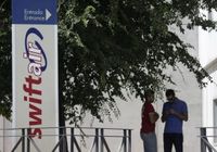 Homens são vistos na entrada da sede da companhia aérea privada espanhola Swiftair, perto de Madri