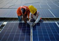 Operários instalam painéis solares na Índia